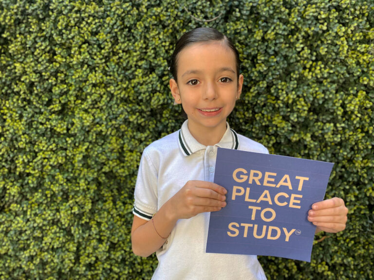 Estudiante de primaria ITYC sosteniendo emblema Great Place to Study®